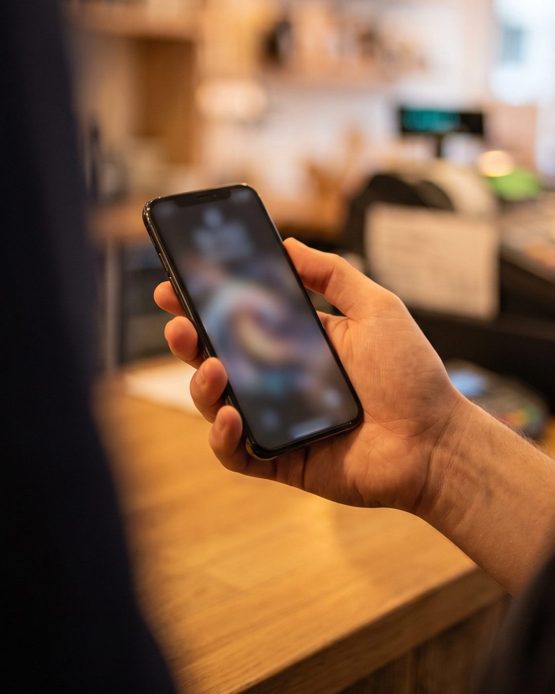 Cliente conferindo no celular a nota fiscal recebida, junto ao balcão da loja